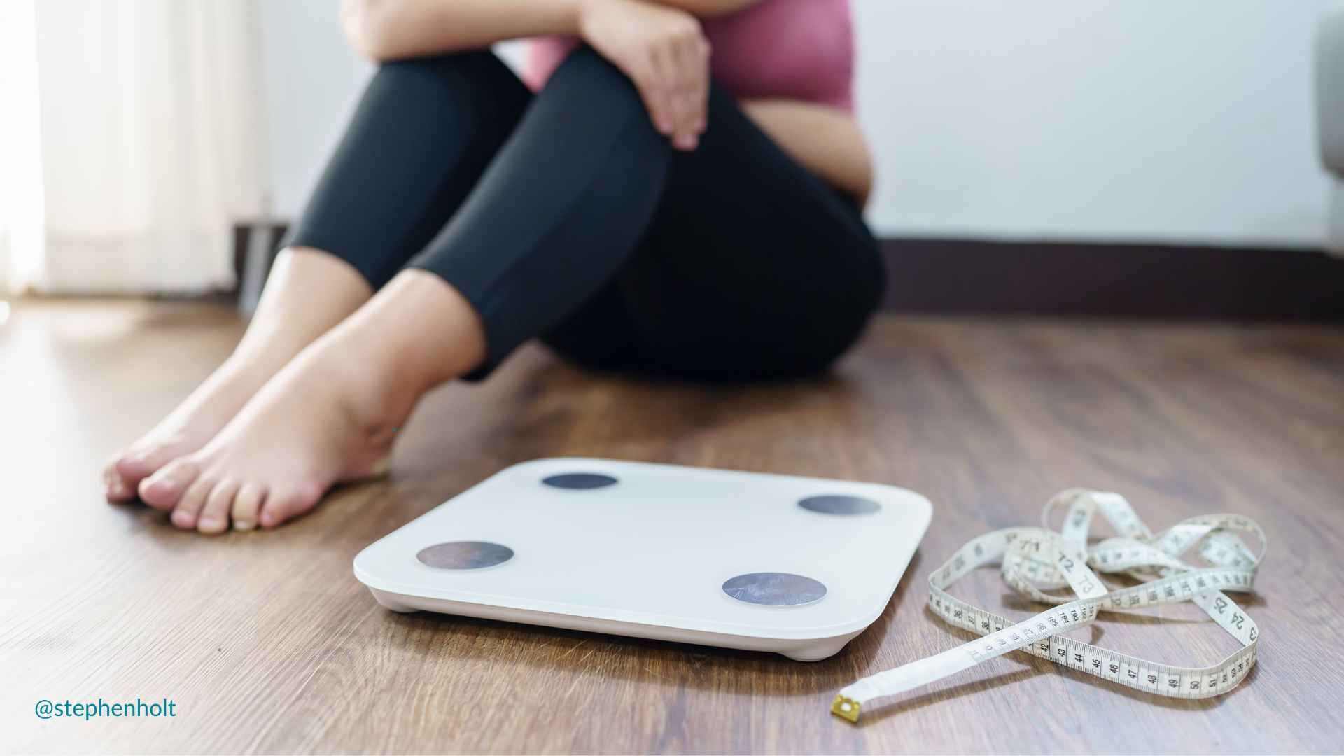 a person sitting on the floor next to a scale